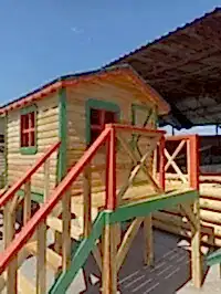 Dükkanda çekilmiş ahşapın turuncu ve yeşil renk uyumunu gösteren çocuk oyun evleri görseli