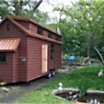 Yeşil orman içinde kahverengi renkli tekerlekli yürüyen minik ev