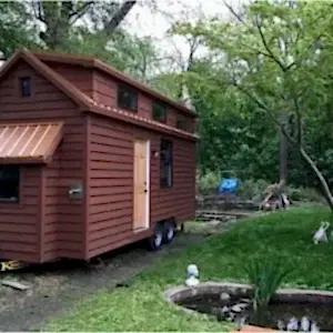 Yeşil orman içinde kahverengi renkli tekerlekli yürüyen minik ev