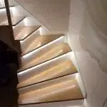 Basamak altlarınandan ışık gelen ahşap beyaz rıhlı beton üstü merdiven