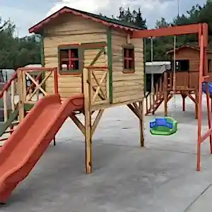 Turuncu renkte kaydırak ve yanında yeşil salıncağı olan yerden yüksek küçük çocuk oyun evi