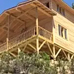 Yerden çekilmiş iki katlı önü verandalı ve yuvarlak ayaklı ahşap ev