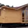 Adanın üzerinde yerler toprak zemin ve arkası ağaçlık alanda konumlanmış önü camekan ve giriş bölümü korunaklı 2+1 Tiny House fiyatları görseli