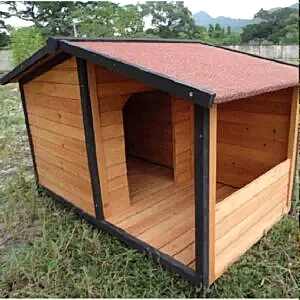 Dost ahşap köpek kulübesi, siyah çerçeveli ve kırmızı çatılı, çim üzerinde.